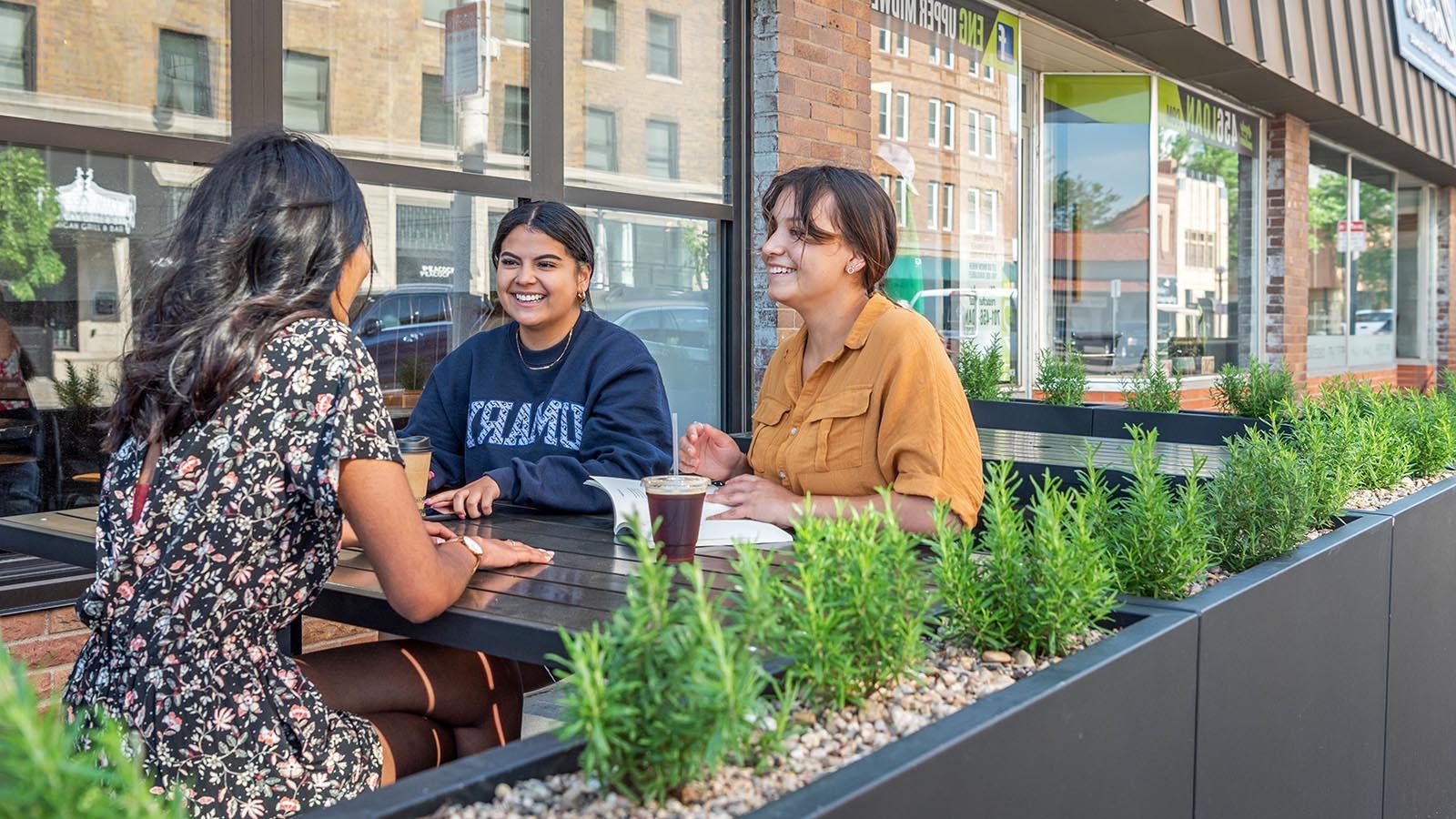 Three happy college students having coffee at a coffee shop in a growing and vibrant downtown Bismarck.